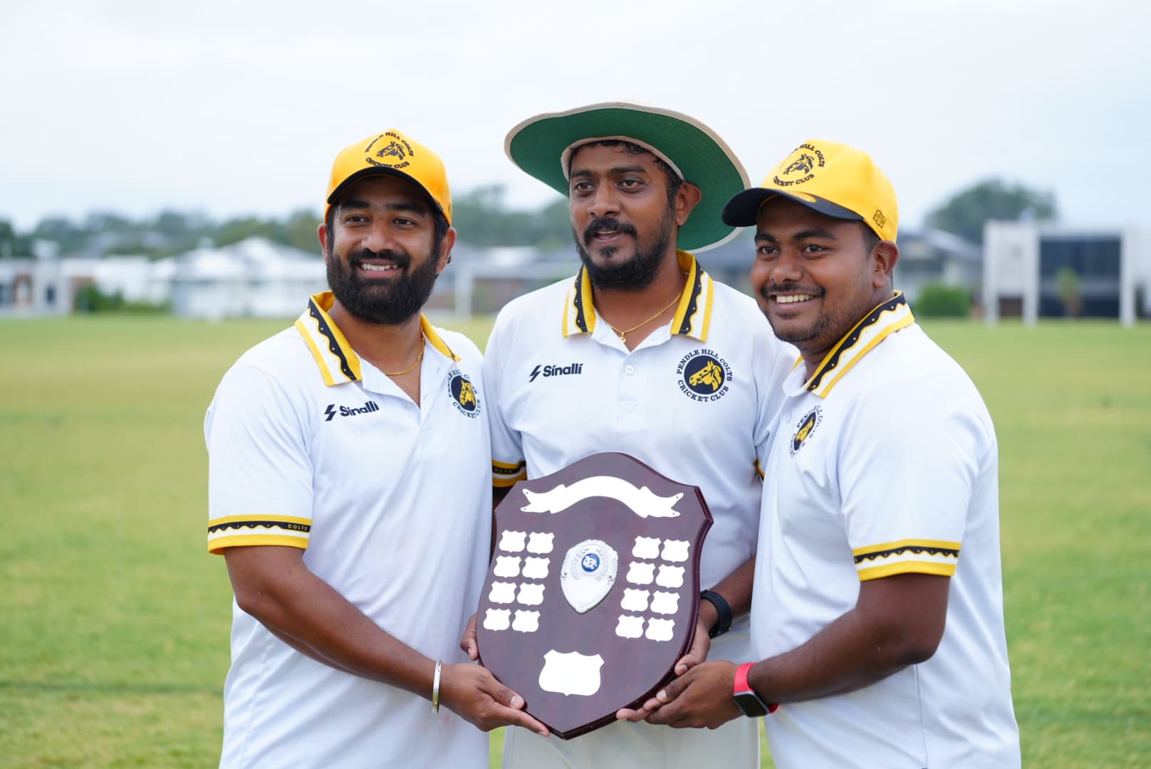 Three smiling GT Comrades teammates stand together with a championship shield